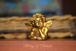 A cherub lays with head on hands, the words say Wings of Thought