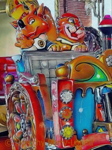 Part of a carousel ride with a brightly coloured carriage with cartoon figure animals with big smiles waving.