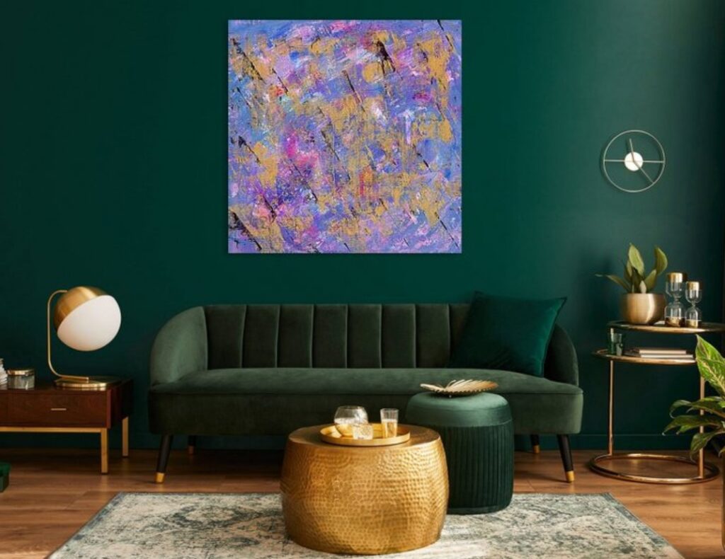 A living room with a dark green wall showcasing an abstract painting with pink, blue, purple and gold all mingling together and streaks of black paint running diagonally down the canvas.